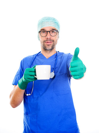 Young doctor with coffee cup and thumb up in front of white backgroundの写真素材