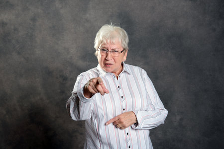 gray hairy elderly woman looking angry and pointing in to the cameraの写真素材