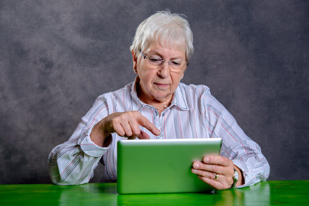 gray hairy elderly woman using tablet pc and smilingの写真素材