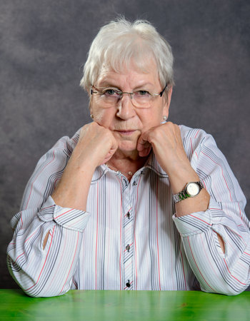 gray hairy elderly woman with glasses  looking  serious in to the cameraの写真素材