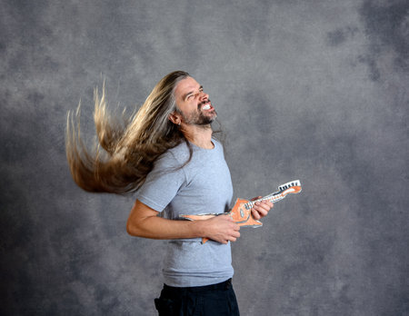 wild long haired young man with cardboard guitarの写真素材