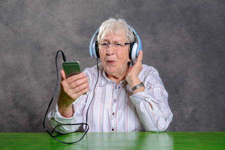 gray hairy elderly woman listening music with headphoneの写真素材