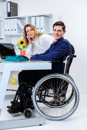 disabled businessman in wheelchair greeting his female colleagueの写真素材