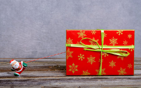 little Santa Claus pulling big red gift boxの写真素材