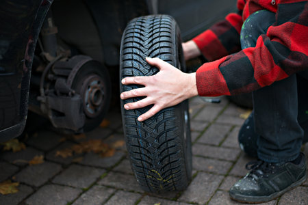 Man in chequered jacket changing tyre on his carの写真素材