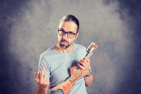 wild young man with cardboard guitar showing middle finger の写真素材