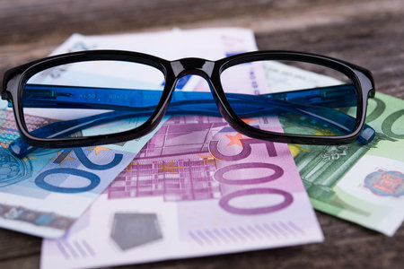 blue glasses frame with money on wooden groundの写真素材