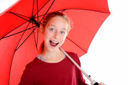 laughing blond girl with red umbrella in frontof white backgroundの写真素材