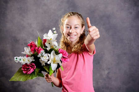 nice blond girl bouquet of flowers and thumb up in front of gray backgroundの写真素材