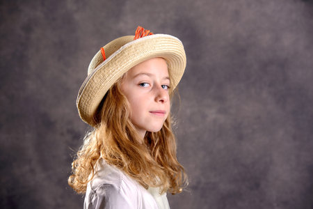nice girl with blond hair in white dress and straw hat looking in to the cameraの写真素材