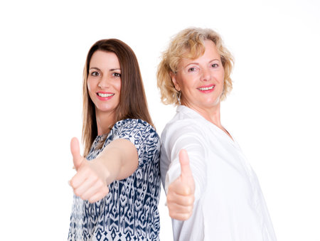 young woman and her mother with thumb up in front of white backgroundの写真素材