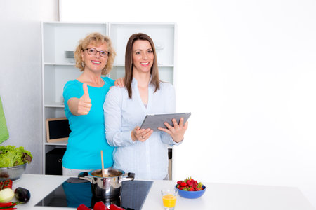 young woman and her mother cooking and baking together in the kitchenの写真素材