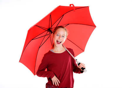 laughing blond girl with red umbrella in frontof white backgroundの写真素材