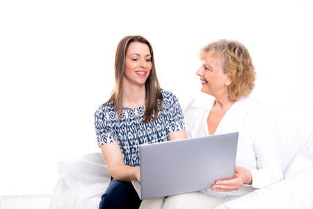 young woman and her mother with laptop in front of white backgroundの写真素材