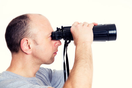 young man in gray shirt looking  through a binocularsの写真素材
