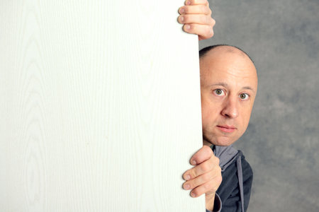 young man with a white advertising board in front of gray backgroundの写真素材