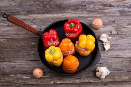 colorful filled pepper,garlic and onion in iron pan on wooden groundの写真素材
