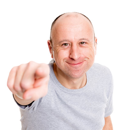 young baldheaded man in front of white background pointing in to the camera and smilingの写真素材