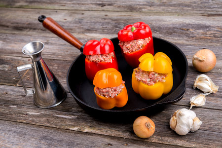 colorful filled pepper,garlic and onion in iron pan on wooden groundの写真素材