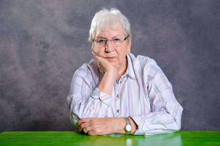 gray hairy elderly woman with glasses  looking  serious in to the cameraの写真素材