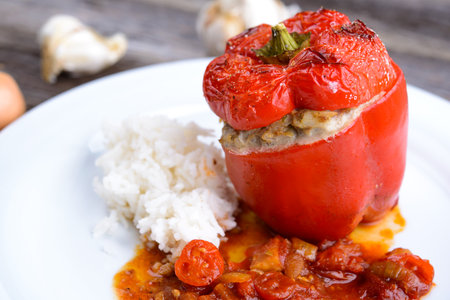 baked red filled pepperwith rice, garlic and onion on wooden groundの写真素材