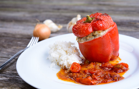 baked red filled pepperwith rice, garlic and onion on wooden groundの写真素材