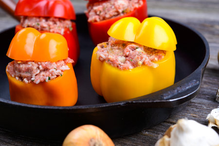 colorful filled pepper,garlic and onion in iron pan on wooden groundの写真素材