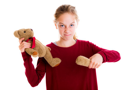 angry blond girl with broken teddy bear in front of white backgroundの写真素材