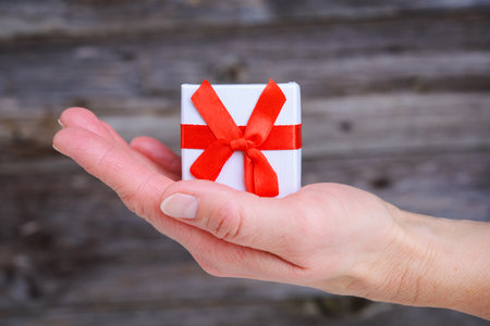 womans hand hold little gift box in front of wooden backgroundの写真素材