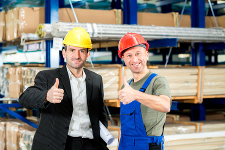 in the factory- young boss and worker with thumb upの写真素材