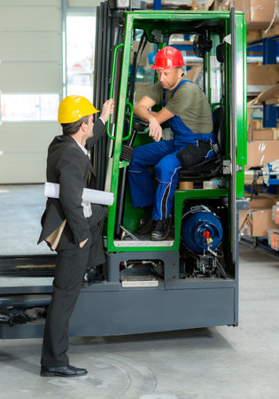 in the factory- young boss and worker in lift truckの写真素材