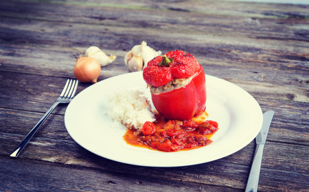 baked red filled pepperwith rice, garlic and onion on wooden groundの写真素材