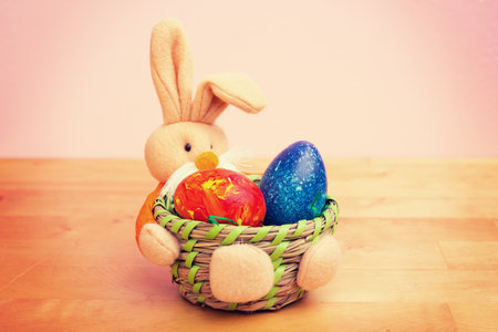 easter bunny in basket with egg in front of pink backgroundの写真素材