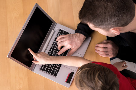 father and son using computer togetherat home