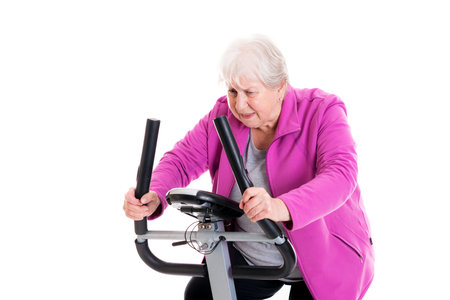 gray-haired female senior with thumb up train with fitness machineの写真素材