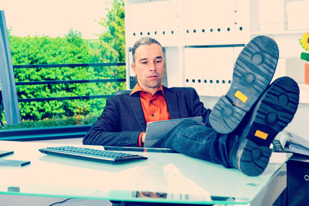 young business man at his desk relaxing with legs on desk の写真素材