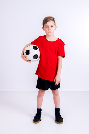 boy in red shirt with soccer ball in front of white backgroundの写真素材