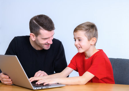 father and son using computer togetherat homeの写真素材