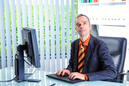 young business man at his desk looking in to the cameraの写真素材