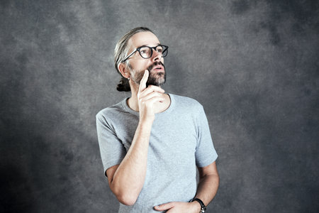 young bearded man with glasses is reflectingの写真素材