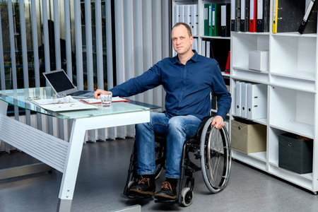 Disabled businessman in wheelchair working in the officeの写真素材