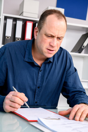 A young business man at his desk writingの写真素材