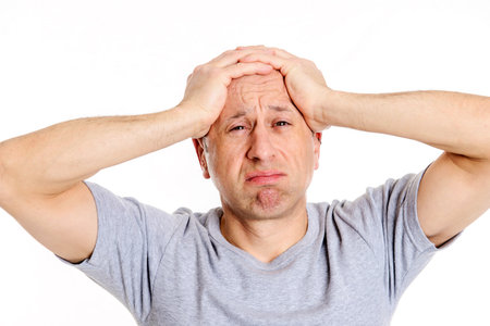 Young man with hands on head looking shockedの写真素材