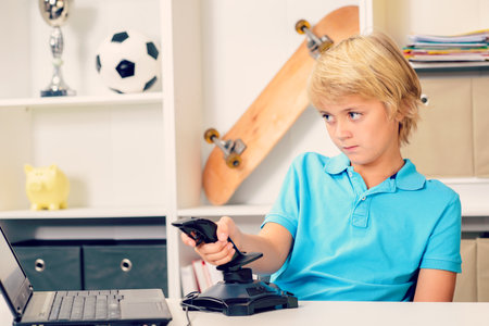 blond boy is playing computer game in his roomの写真素材