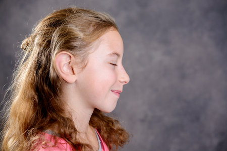 nice girl with blond hair and pink shirt in front of gray backgroundの写真素材