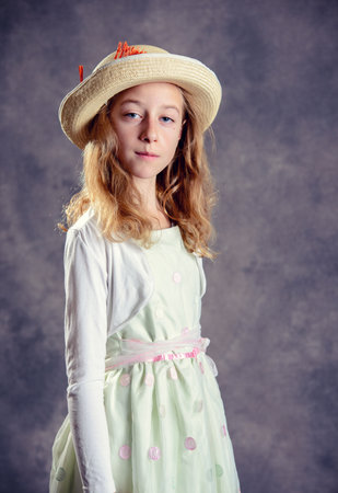 nice girl with blond hair in white dress and straw hat looking in to the cameraの写真素材