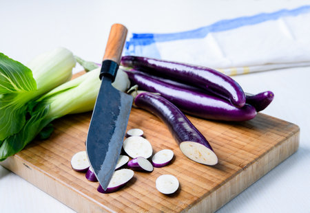 japanese eggplant on wooden board with cooking knife and pak choi saladの写真素材
