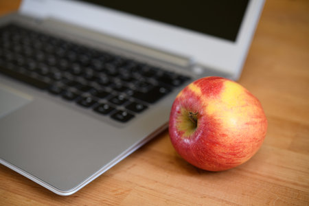 laptop with red apple on wooden groundの写真素材