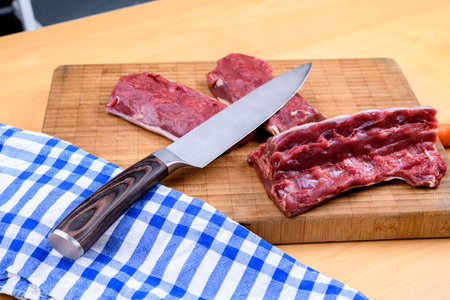 saddle of venison on wooden board with big knifeの写真素材