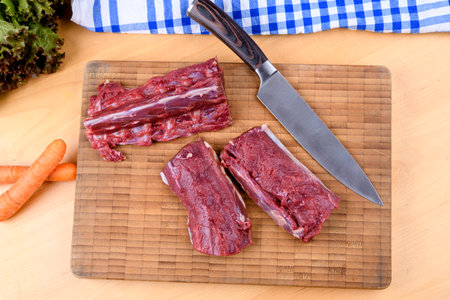 saddle of venison on wooden board with big knifeの写真素材